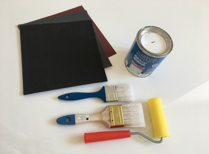 Die Materialien zur Gestaltung eines selbstgestalteten kleinen Tisches: Pinsel, Lack, Schleifpapier